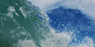 一个完美的玻璃美丽的波POV波浪打破相机在加利福尼亚夏天的阳光浅沙滩上。慢动作在红龙上以300FPS的速度拍摄。