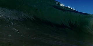 完美的巨大桶状波浪POV，海浪打破了相机在加利福尼亚夏天的阳光浅沙滩上。慢动作在红龙上以300FPS的速度拍摄。