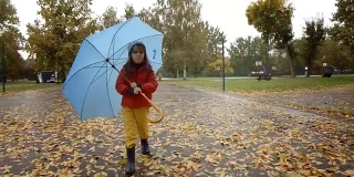 带着伞在雨中行走的孩子。