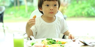 小孩穿着白衬衫吃早餐。