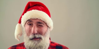 灰色背景上的老人眨眼和微笑的圣诞老人的帽子。