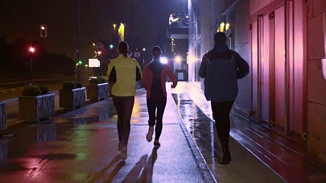 朋友们在一个雨夜在城市里跑步