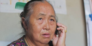一位年长的亚洲妇女正在用手机打电话。