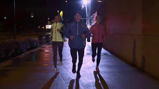 一个男人和两个女人晚上在城市里跑步
