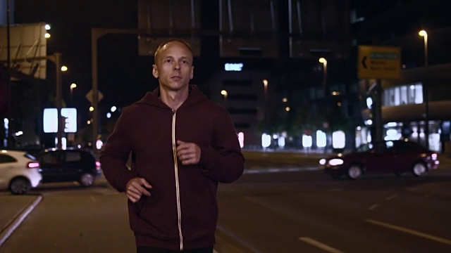 SLO MO TS男子晚上在城市街道上慢跑