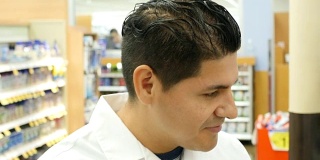 中年西班牙裔药剂师在超市药房检查数字平板电脑的库存