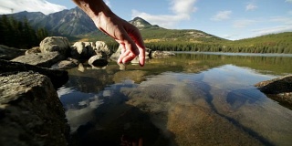 手指触碰湖面。日落