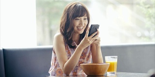 美丽微笑的亚洲女孩使用智能手机并把它放下