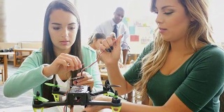 两个漂亮的西班牙少女在STEM学校合作创造机器人