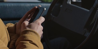 男人在车里用手机发短信。