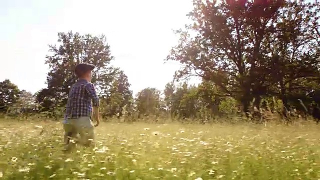 一个小男孩在一个阳光明媚的日子跑过草地