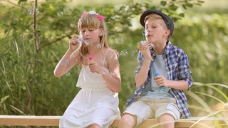小男孩和小女孩在人行桥上吹泡泡视频素材模板下载