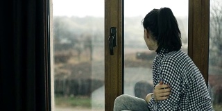 年轻女子坐在窗边。