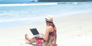 女孩在沙滩上玩笔记本电脑