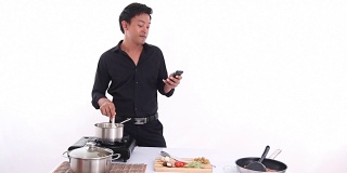 男人做饭和看手机在白色房间的厨房