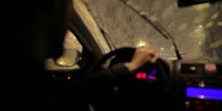 一个年轻人在暴风雪的夜晚开车。