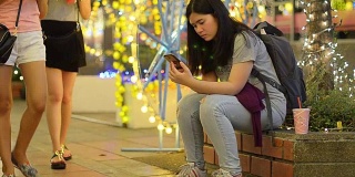 panning:女人在晚上的庆祝活动中专注于使用智能手机