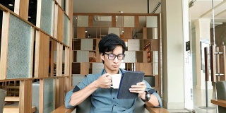 在咖啡店喝咖啡和用平板电脑的男人