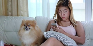 女人用手机和可爱的狗