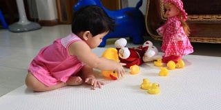 亚洲婴儿坐在地板上玩黄色的鸭子娃娃