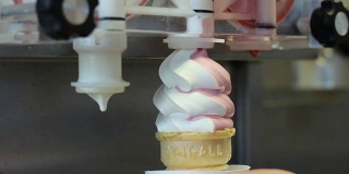 从机器上制作扭曲的粉色和白色冰淇淋蛋卷