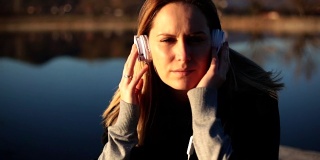 戴着耳机的女人在湖边码头上听音乐