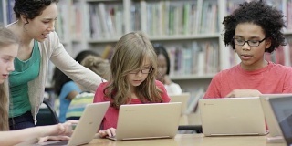 小学生在图书馆用笔记本电脑工作