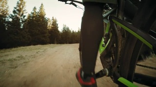 POV骑自行车的人的腿在森林的道路上在阳光视频素材模板下载