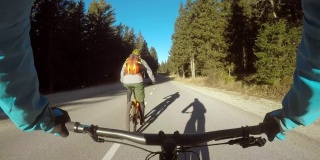POV两个骑自行车的人在穿过森林的路上骑着他们的自行车