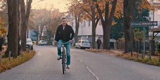 一名年轻人骑着自行车沿着树木环绕的道路行进