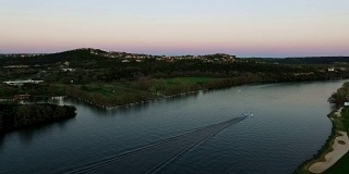 金星带的颜色地平线日落在德州山乡村大厦和德克萨斯州奥斯汀最好的地区，一艘快艇滑向水面市中心ATX高远角