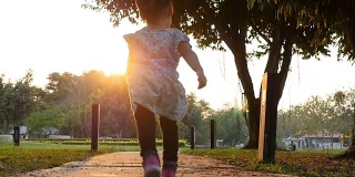 慢动作小女孩在日落时在公园里跑步