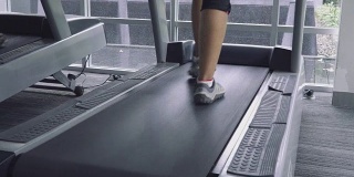 在健身房跑步机上跑步者的脚的特写