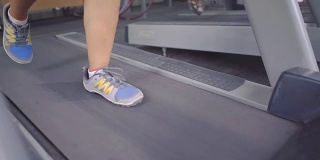 在健身房跑步机上跑步者的脚的特写