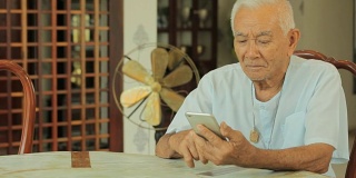 快乐的亚洲老人在家里用手机