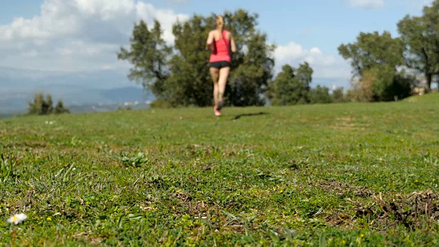 镜头前的女运动员在草地上奔跑