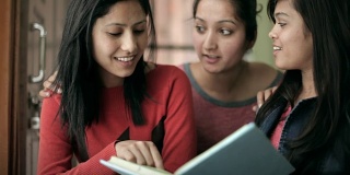 青少年晚期的快乐女孩学生一起学习一本书。