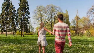 慢镜头:情侣手牵着手穿过公园视频素材模板下载