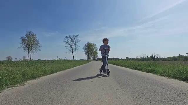 Child riding scooter on country road