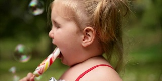 女孩吃棒棒糖。缓慢的运动。