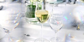 在水晶窗帘后面的精致餐桌上倒白葡萄酒
