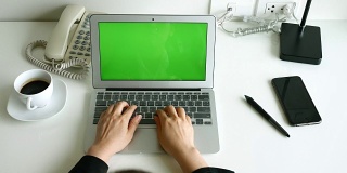 女商人在办公桌上打开笔记本电脑，用绿色屏幕打字，4K(超高清)