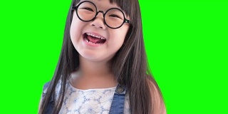 小女孩在绿色屏幕上笑和转动的特写