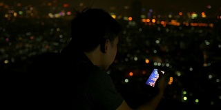 一个亚洲男人晚上在城市里一边打电话一边挂断电话