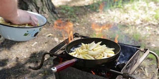 男人在篝火上准备炸土豆。