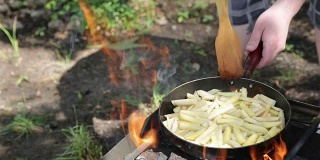 男人在篝火上准备炸土豆。