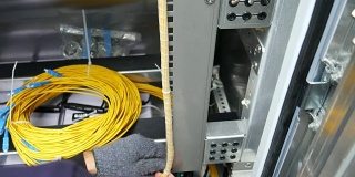 技术人员正在重新整理电信设备架上的光缆