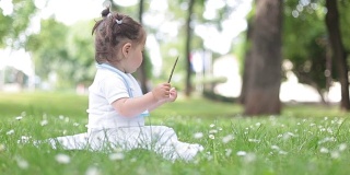 小女孩坐在草地上，抚摸着她的树枝，享受着大自然
