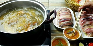 吃泰国菜的亚洲人。在一锅热水中放入鱼肉