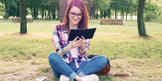 一个年轻女子在大自然中阅读电子书
